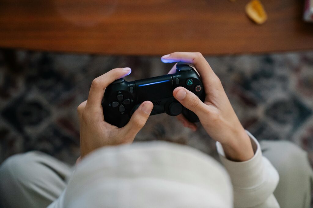 From above of crop unrecognizable male with console controller playing video game in living room