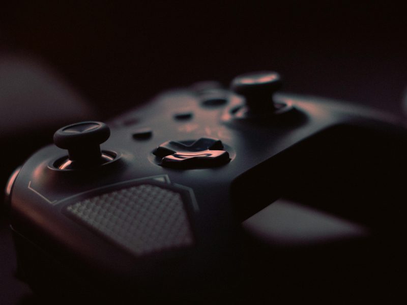 A close-up shot of a game controller in low light, highlighting its design and buttons.