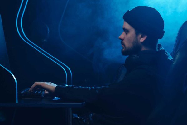 A man working on a computer in a dimly lit room, focusing on cybersecurity.